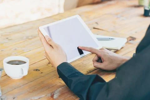 Man using tablet on table in coffee shop with vintage toned filter. Stock Photos