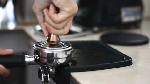 Man is using a tamper to press freshly ground morning coffee into a coffee ta Stock Footage 83028837