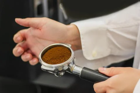 Man is using a tamper to press freshly ground morning coffee into a coffee ta Foto stock