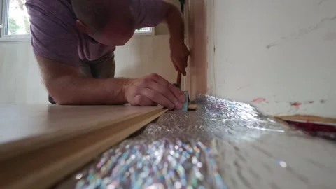 Man using tapping block and hammer to install laminate flooring planks. 스톡 동영상 341084133