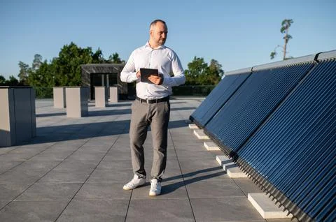 Man using technology to inspect rooftop solar installation 스톡 사진