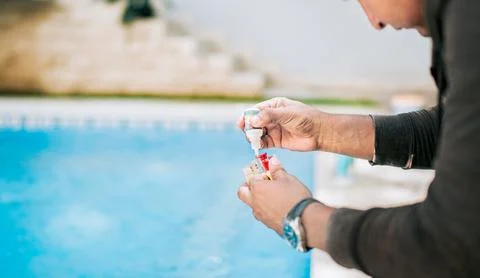 Man using tester kit to measure chlorine and ph in swimming pools. Person t.. Stock Photos
