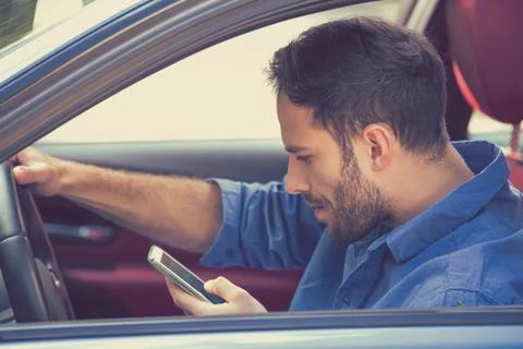 Man using texting on mobile phone while driving a car Stock Photos