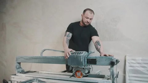Man using a tile cutter to cut tiles for a flooring project Stock Footage 317378137