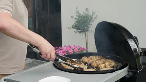 Man using tongs to flip bread slices on an outdoor charcoal grill grate Stock Footage 340163412
