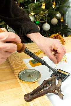 A man is using a tool to fix the wiring of a Christmas tree garland. Tools ar Stock Photos