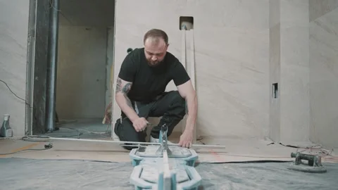 Man using tools to install tile in a construction area during daytime Stock Footage 317377932