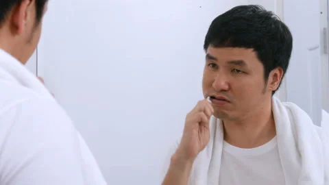 Man using toothbrush to brushing teeth in the bathroom mirror Stock Footage 153704096