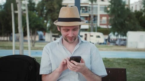 Man using touch Mobile Phone outdoor in City Park with Palms, man walking with Stock Footage 221860042