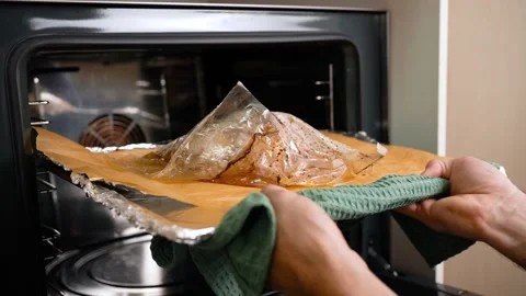 A man using a towel takes out a baking tray with a ready chicken in his sleeve. Stock Footage 250309241