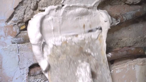 Man using a trowel to apply plaster over pipes in a wall. Stock Footage 99451954