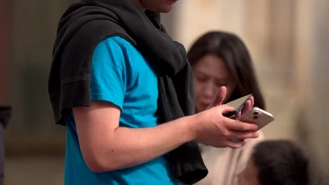 A man using two smartphones at the same time in a city centre with people Stock Footage 279923806