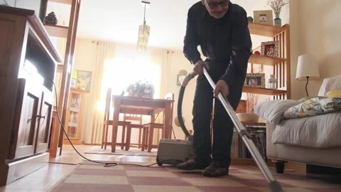 Man Using Vacuum Cleaner in Cozy Living Room Amid Natural Light Video stock 307740078