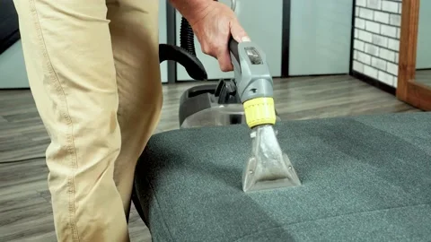 Man using vacuum cleaner equipment vacuuming sofa in room, cleaning furniture Stock Footage 206630706