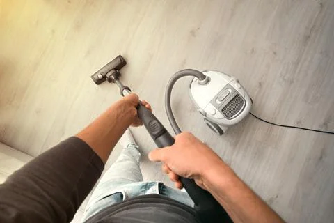 Man using a vacuum cleaner at home. Man cleaning house. House keeping Stock Photos