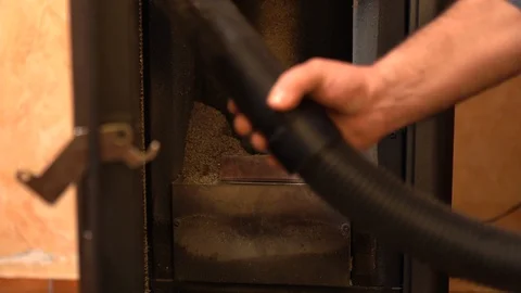 Man using vacuum cleaner for removing rubbish from pellet stove, biofuel concept Stock Footage 128594214