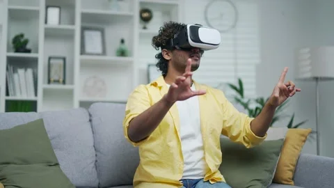 Man using virtual reality headset while sitting on sofa at home Happy young male Stock Footage 235505012