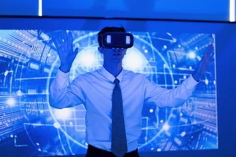 Man using virtual reality headset in a blue-lit room during a tech demonstr.. Stock Photos