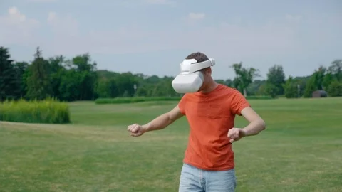A man using a VR headset and playing a virtual game in the park Stock Footage 112810509