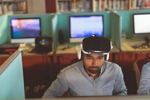 Man using VR headset in office, focused on computer screen, working intently Stock-Fotos