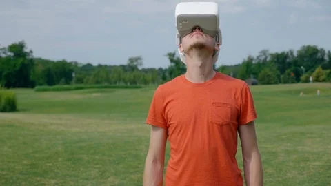 A man using a VR headset in the park and turns his head up Stock Footage 112807156