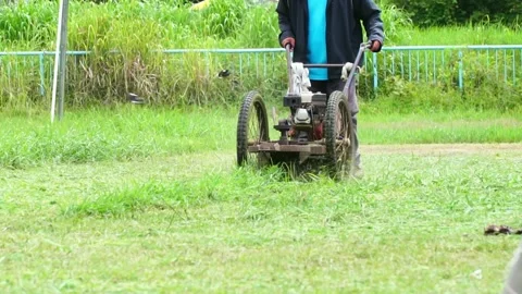 Man using a walk-behind lawnmower on a football field. 스톡 동영상 169245845
