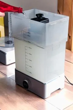 Man using a wash machine to clean a transparent 3d resin object Stockfoto's