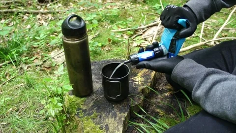 Man Using Water Filter to Filter and Purify Water. Wilderness Survival Skills. Stock Footage 306536865