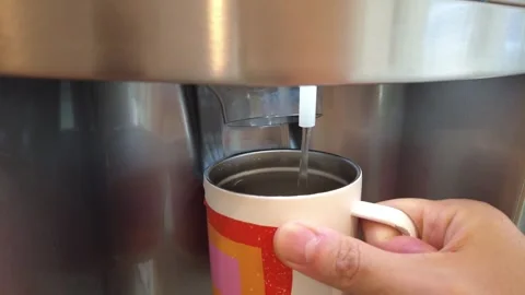 Man using the water filter on the refridgerator to fill his cup with cold water Stock-Footage 244439411