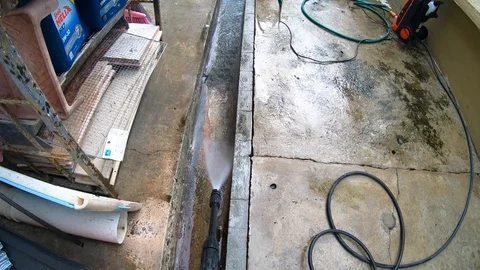 A man using water pressure washer to wash dirty floor Stock Footage 127730404