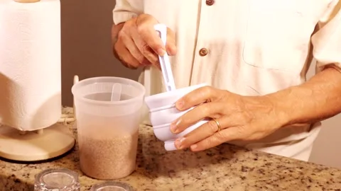 Man using with a white plastic mortar and pestle crushing flax seeds 스톡 동영상 334689596