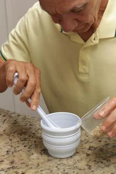 Man using a white plastic mortar to crush herbs Stock Photos