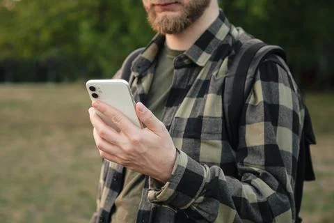 Man using white smartphone on blurred nature background, close up. Stock Photos