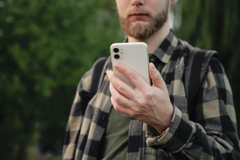 Man using white smartphone on blurred nature background, close up. Stock Photos