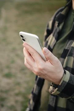 Man using white smartphone on blurred nature background, close up. Stock-Fotos