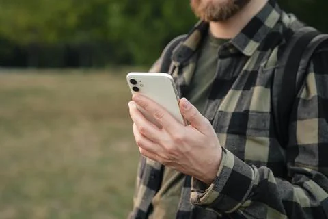 Man using white smartphone on blurred nature background, close up. Stock Photos