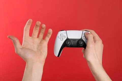 Man using wireless game controller on red background, closeup Stock Photos
