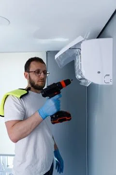 Man Utilizing a Power Drill for Installing a Wall-Mounted Air Conditioning Unit Stock Photos