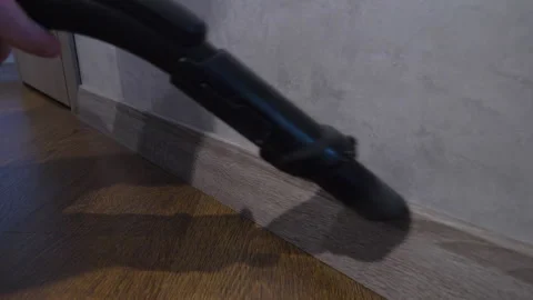 Man vacuuming dust on baseboard in apartment. Apartment cleaning Stock Footage 336559174