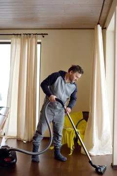 Man vacuuming wooden floor at home Stock Photos
