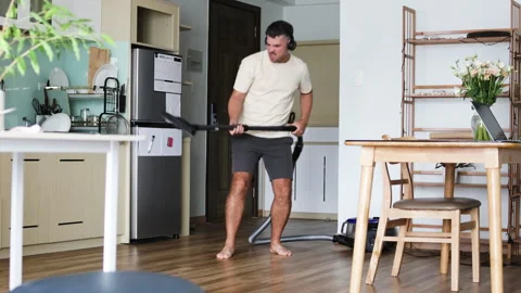 A man vacuums the apartment while dancing. Stock Footage 310218041