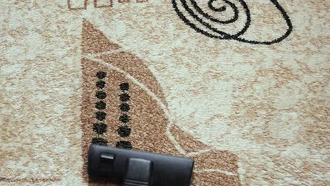 A man vacuums a beige carpet with patterns in a house or apartment. Stock Footage 130542179