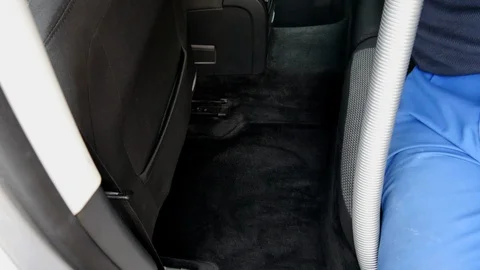 A man vacuums the car interior Stockbeeldmateriaal 98251569