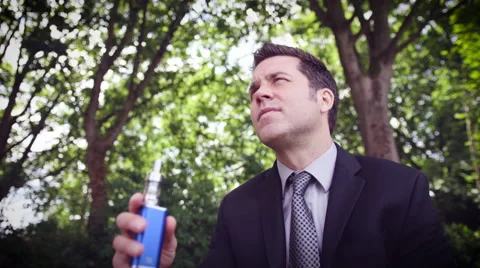 Man vaping electronic cigarette in park Stock Footage 64454774