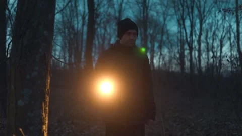 A man ventures into the nighttime forest, guided by a flashlight. Stock Footage 301244820