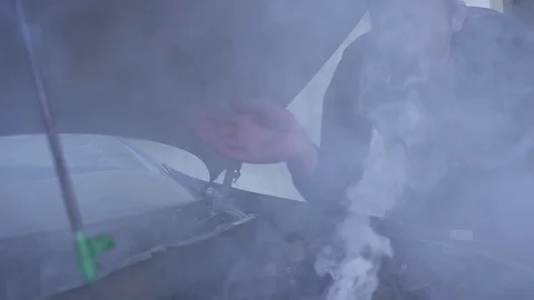 A man is very frustrated while trying to evaluate his smoking car engine. Video stock 118781912