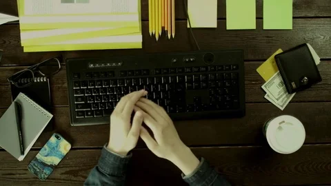 The man very quickly types on the keyboard on his desk. Stock Footage 82009398