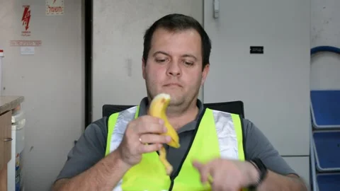 Man in vest eats banana on workplace 動画素材 143277551