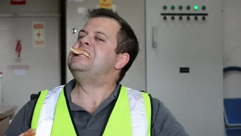 Man in vest eats slice of pizza on workplace Vídeo Stock 143452025