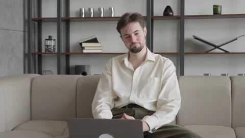 Man On Video Call Shaking Head In Disagreement While Sitting On Sofa At Home Stock Footage 306696593
